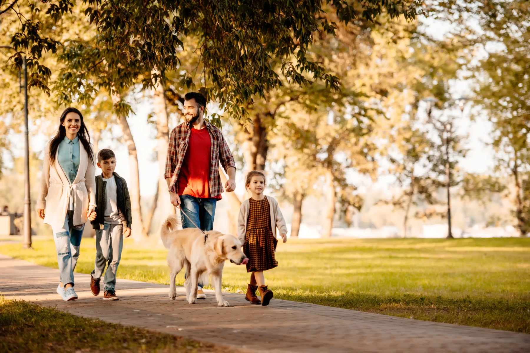 A young family walking a dog in a park